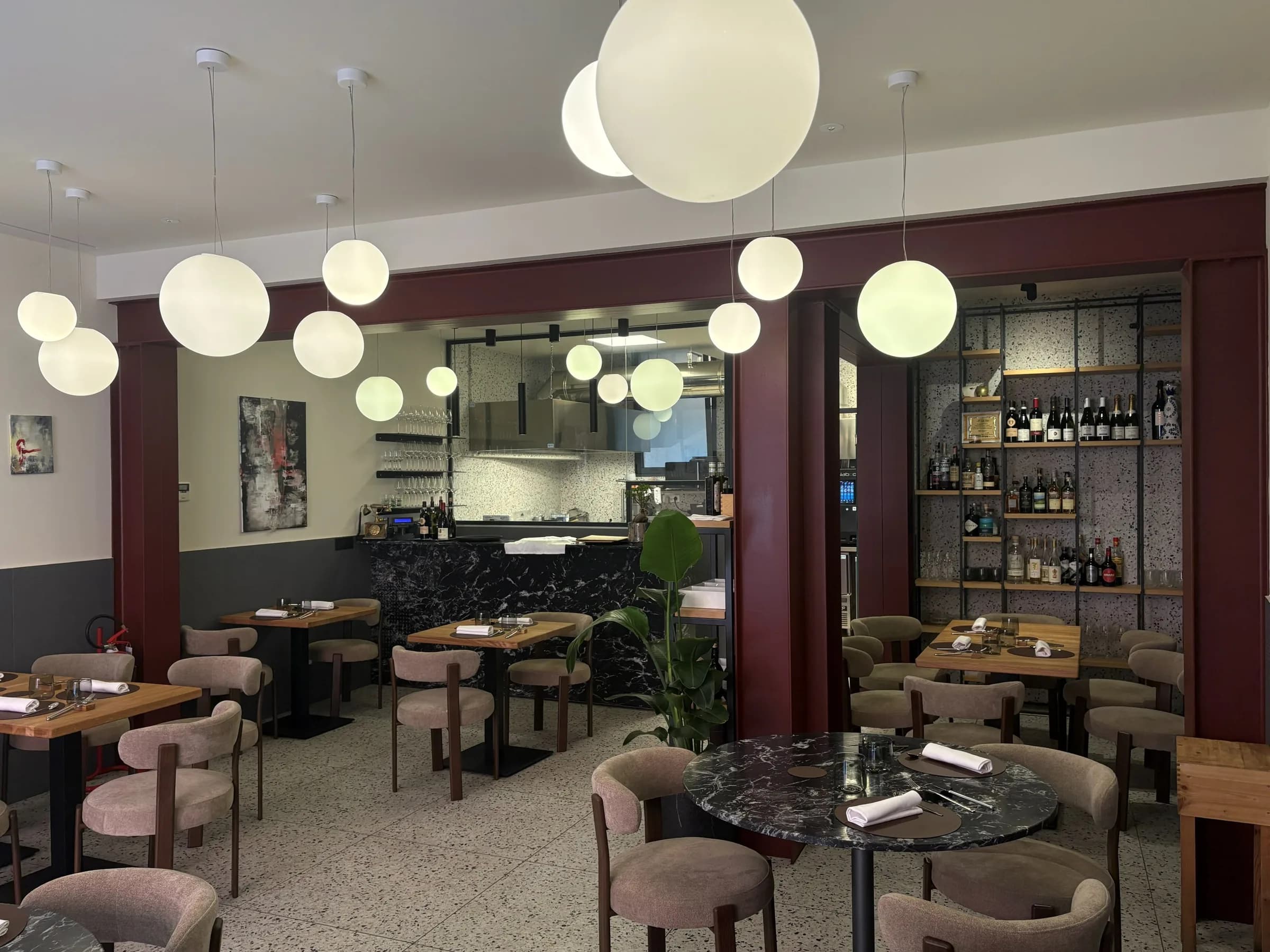 Sala principale di Materia Osteria Contemporanea, Ferrara, con sfere luminose e cucina a vista