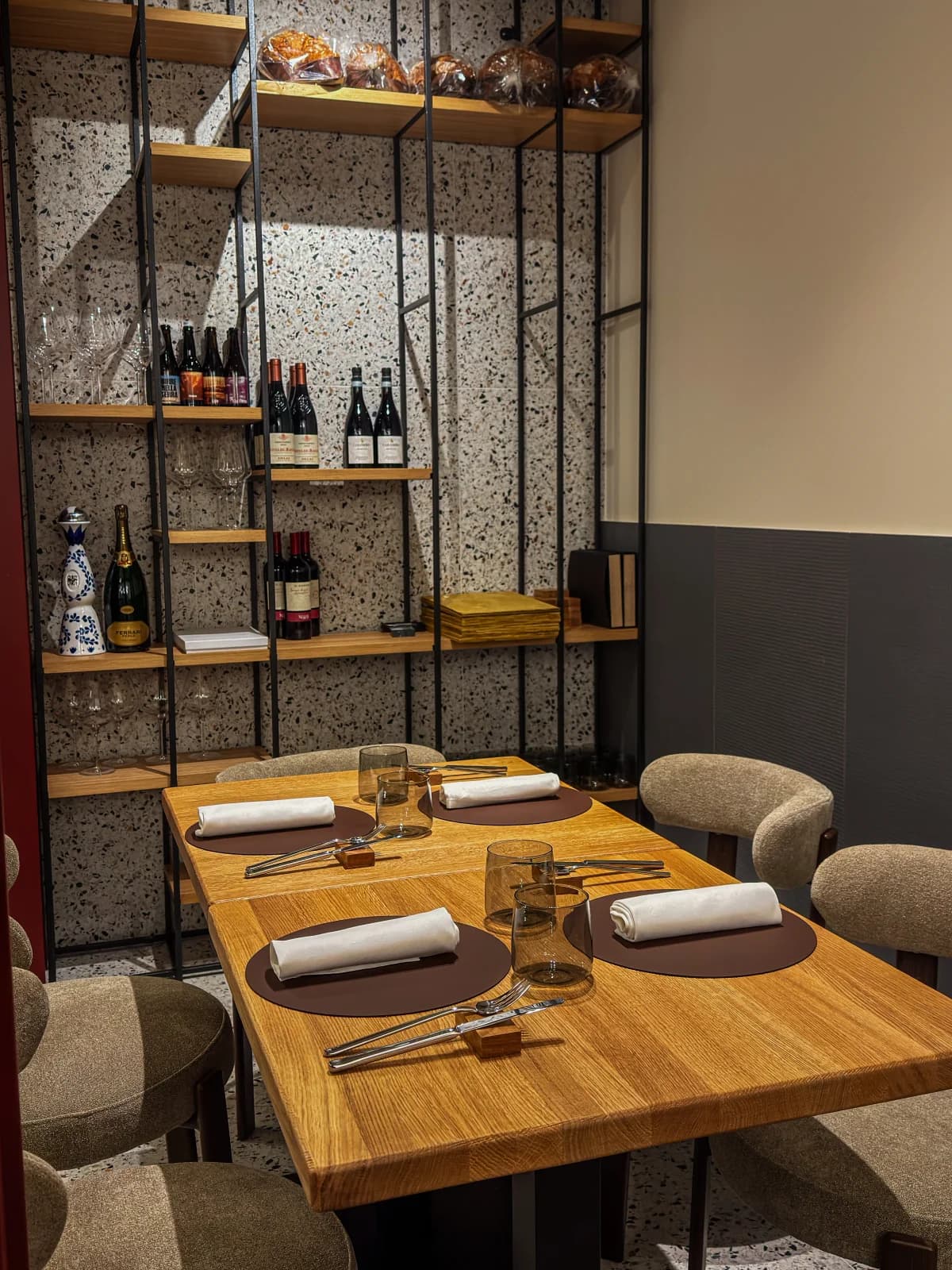 Tavolo apparecchiato per quattro con scaffalatura di vini sullo sfondo, sala di Materia riservata per un evento privato