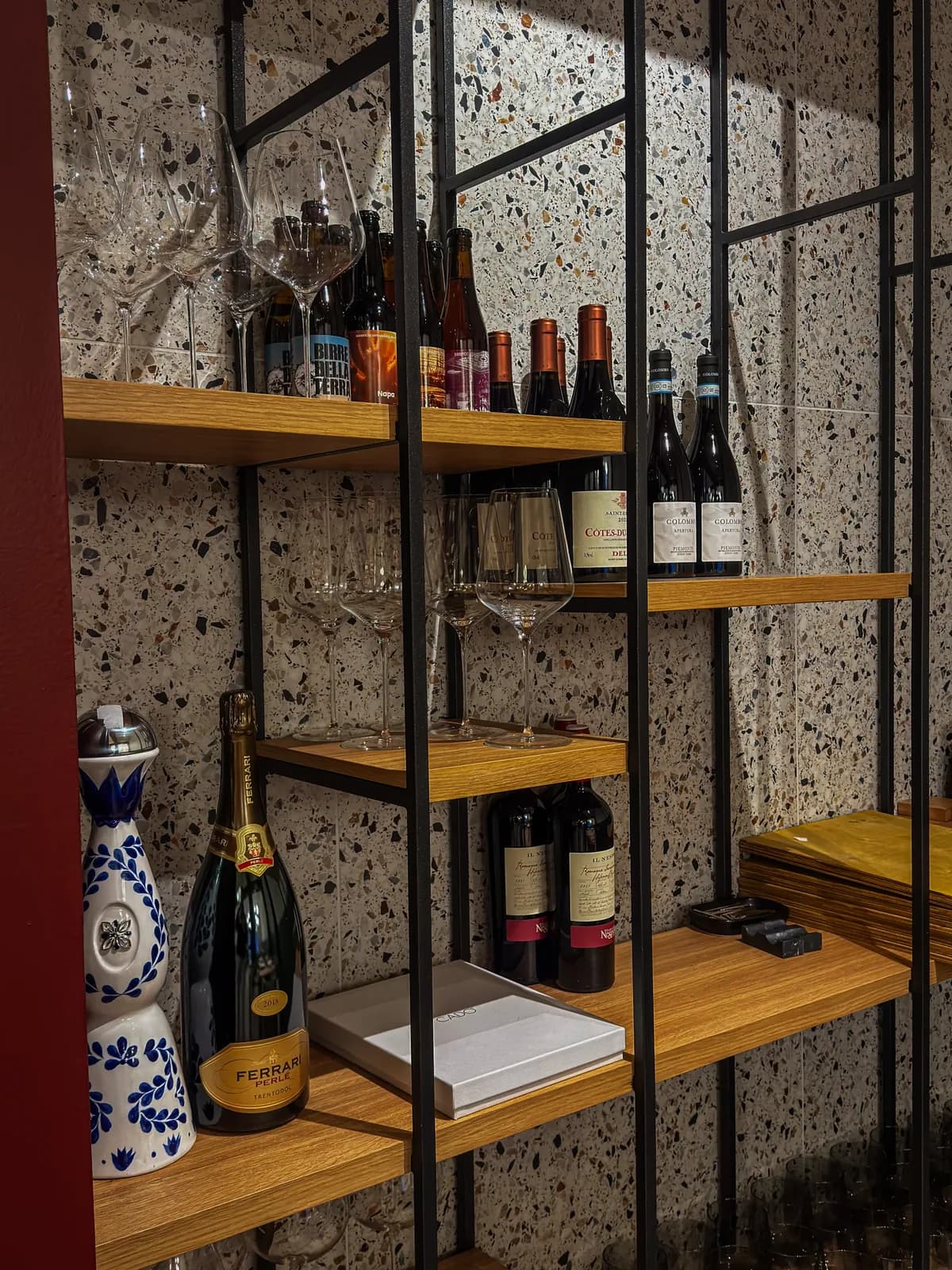 Scaffale in ferro e rovere con bottiglie di vino, birre artigianali e calici, cantina di Materia Osteria Contemporanea