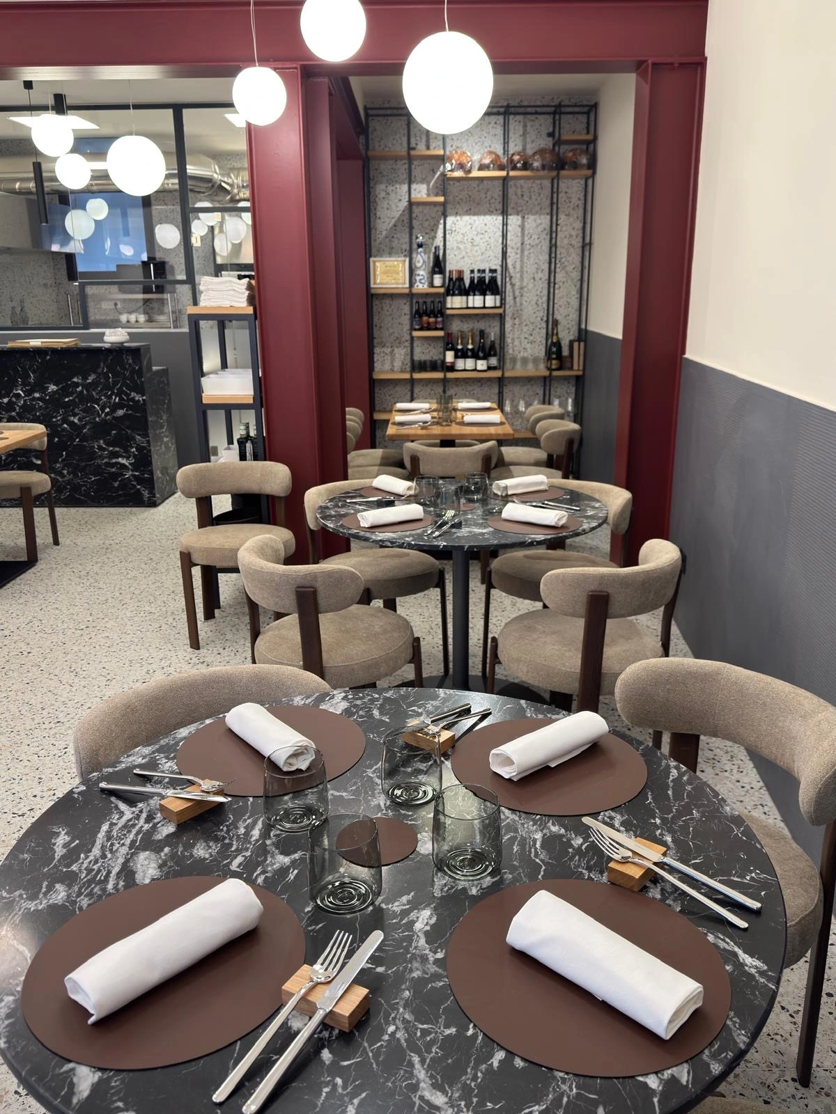 Sala di Materia apparecchiata per la cena, tavoli in marmo e cucina a vista